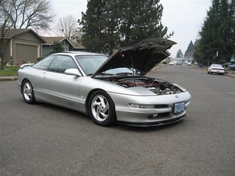 1994 Ford Probe - A silver 1994 Ford Probe coupe is parked on a street with its hood open, revealing the engine compartment.