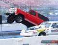 1979 Ford Bronco - A red pickup truck is in mid-air during a race, while a white sedan is visible below.