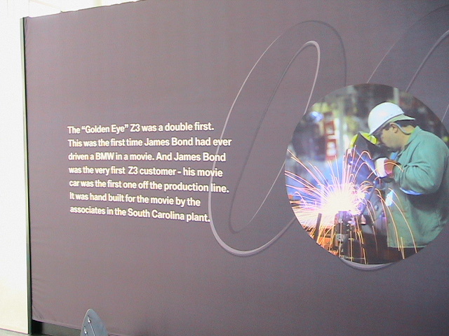 Exhibit sign about the GoldenEye BMW Z3 with a circular photo of a worker welding, sparks flying