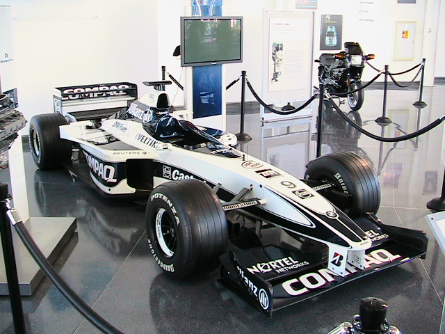 White and blue BMW Williams Formula 1 car with Compaq sponsorship displayed in a museum, front three-quarter view