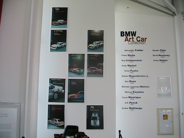 BMW Art Car Collection exhibit wall with framed car posters and a list of artists' names and years