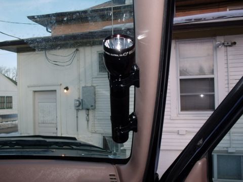 1996 Ford Bronco - Maglite flashlight attached to the interior pillar of a vehicle, with a building visible through the window.