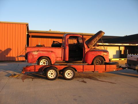 1952 Ford Pickup - Red 1952 Ford Pickup truck loaded onto a trailer with its hood up.
