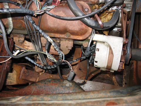 1952 Ford Pickup - Close-up view of an engine bay, highlighting the alternator, various wires, and signs of rust on the engine block and surrounding metal.