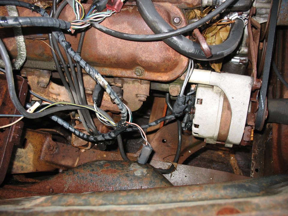 Engine bay detail showing alternator, wiring, and rusty engine components