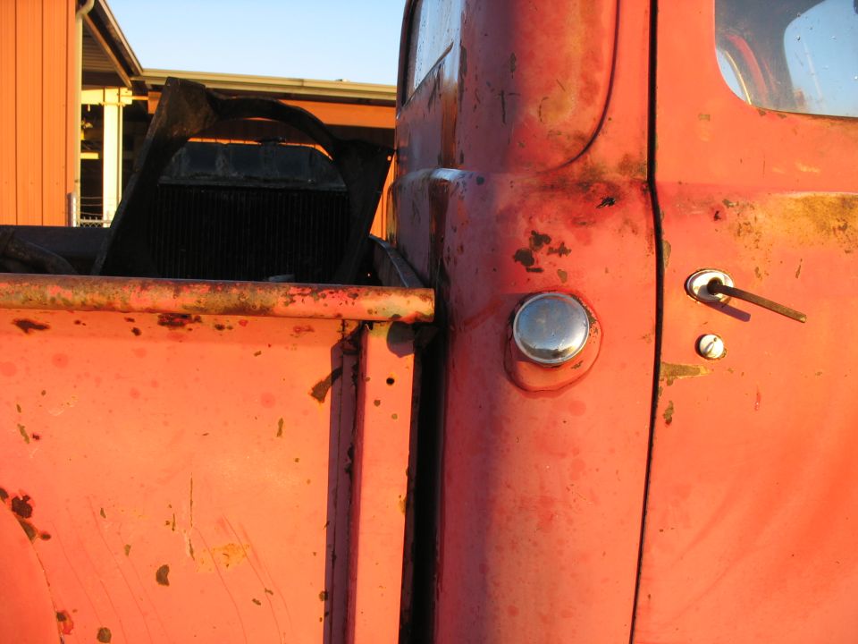 close-up of red pickup truck door and bed, radiator in background