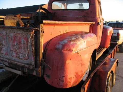 1952 Ford Pickup - A red pickup truck is loaded onto a trailer, with a white truck visible behind it.
