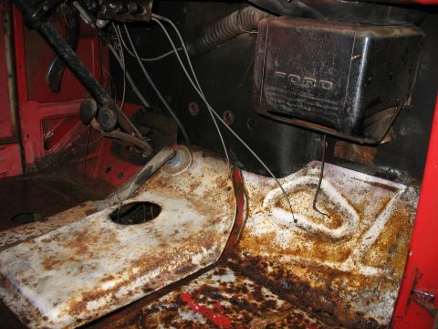 1952 Ford Pickup - The interior of a 1950 Ford F-series pickup reveals significant rust on the floor pans and a prominent 'FORD' emblem on the heater unit.