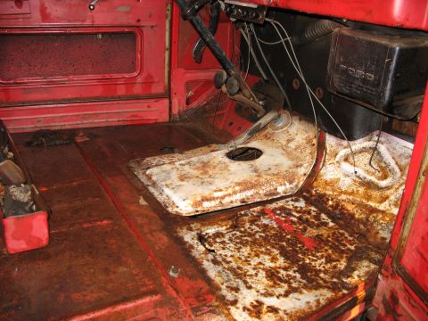 1952 Ford Pickup - The interior of a 1952 Ford Pickup reveals significant rust on the floor and dashboard, with the Ford emblem visible.
