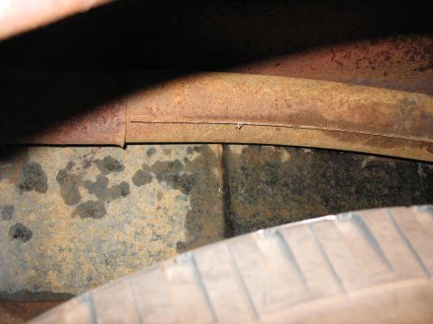 1952 Ford Pickup - Close-up of a rusted vehicle frame rail and tire, showing undercarriage details.