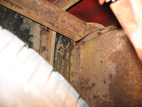 1952 Ford Pickup - The underside of a vehicle shows significant rust and wear on its frame components and tire.