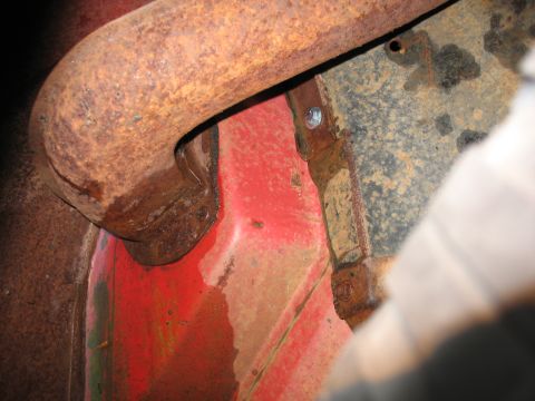 1952 Ford Pickup - A close-up view of a rusted exhaust pipe and red painted metal components, showing signs of wear and tear.