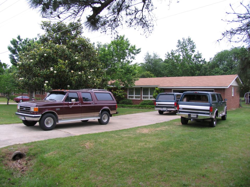 Maroon SUV with tan trim parked on driveway, two other SUVs behind it