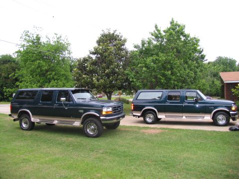 1995 Ford C-350 (Centurion Conversions) - Two 1995 Ford C-350 Centurion Conversions SUVs are parked on a grassy area in front of trees and a house.