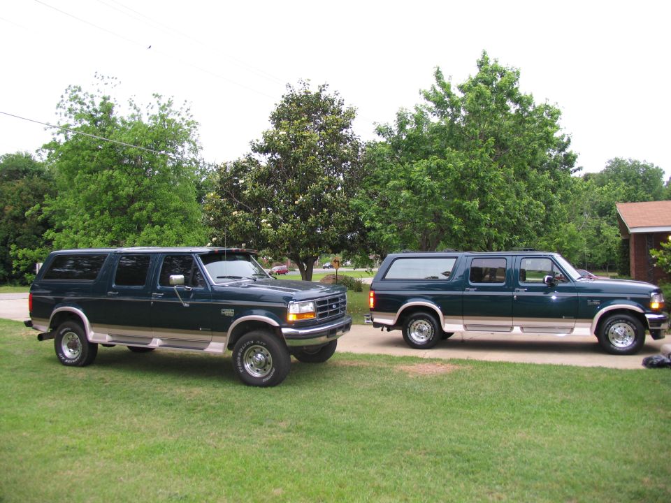 Two dark green 1995 Ford C-350 Centurion Conversions SUVs parked side-by-side on a lawn