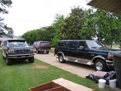 1995 Ford C-350 (Centurion Conversions) - Three Ford SUVs are parked in a driveway on a cloudy day, with trees and houses in the background.