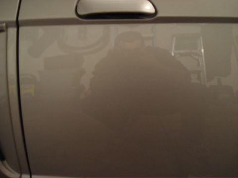 1998 Ford Taurus - Reflection in the vehicle's side panel shows a person, ladder, and bicycle wheel.