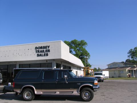 1995 Ford C-350 (Centurion Conversions) - A dark green SUV with tan trim is parked in front of Dorsey Trailer Sales under a clear blue sky.