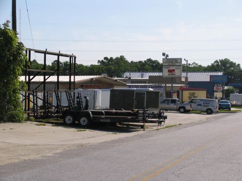 1995 Ford C-350 (Centurion Conversions) - A silver pickup truck is parked in an industrial area with several trailers and buildings visible.