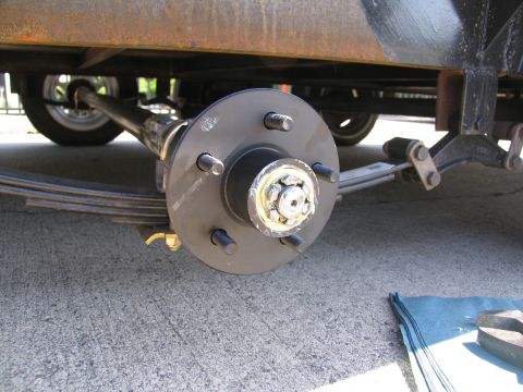 1995 Ford C-350 (Centurion Conversions) - Close-up view of a trailer's axle, leaf springs, and wheel hub assembly.