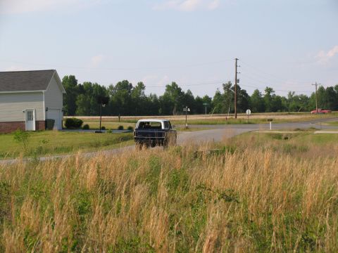 1995 Ford C-350 (Centurion Conversions) - A classic Ford F-Series truck drives down a country road, with another vehicle in the background.
