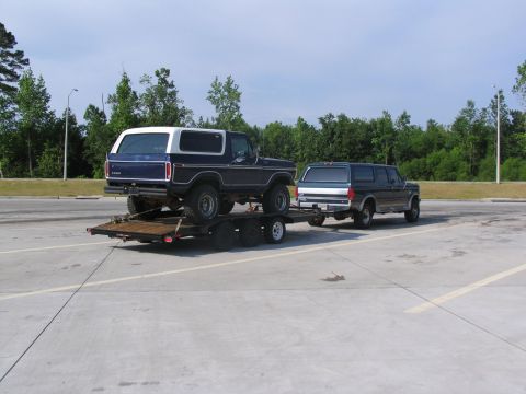 1995 Ford C-350 (Centurion Conversions) - Two Ford SUVs are visible, one a Bronco on a trailer and the other towing it.