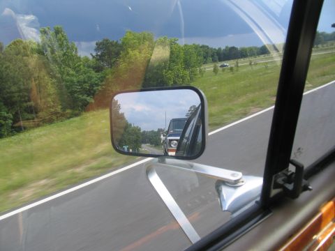 1995 Ford C-350 (Centurion Conversions) - Reflection of a pickup truck in the side mirror, showing its front grille and headlights.
