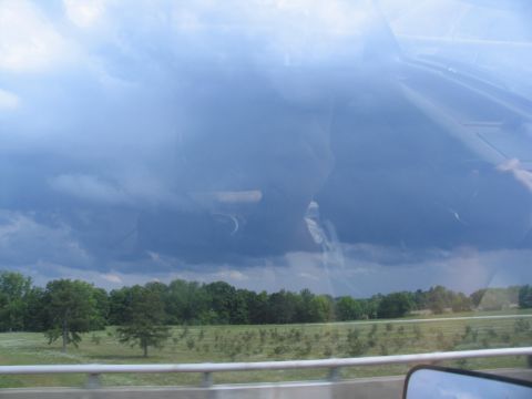 1995 Ford C-350 (Centurion Conversions) - Stormy weather approaches over a rural landscape, seen through a vehicle's window.