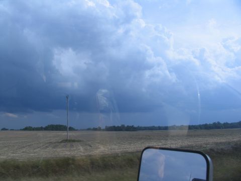 1995 Ford C-350 (Centurion Conversions) - A reflection in the side mirror shows a person looking out at a dramatic sky over a harvested field.