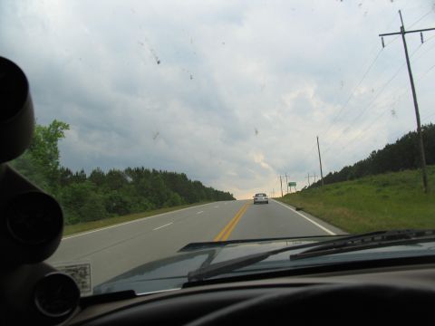 1995 Ford C-350 (Centurion Conversions) - Driving on a highway with a cloudy sky and trees lining the road. Another car is visible ahead.
