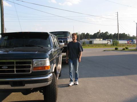 1978 Ford Bronco - A man stands next to a dark green Ford truck, with another vehicle behind it.