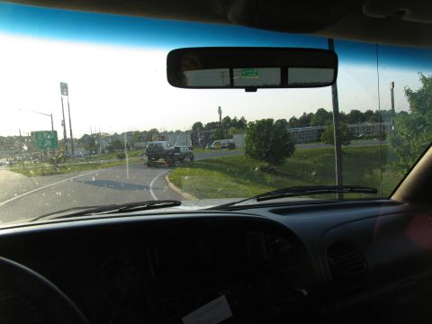 1978 Ford Bronco - Two SUVs are transported on a trailer along a highway on a sunny day.