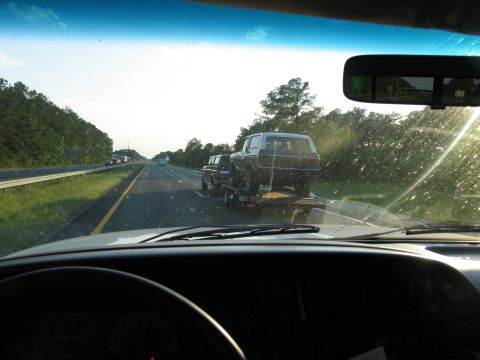 1978 Ford Bronco - A 1978 Ford Bronco is transported on a trailer down a highway during the day.