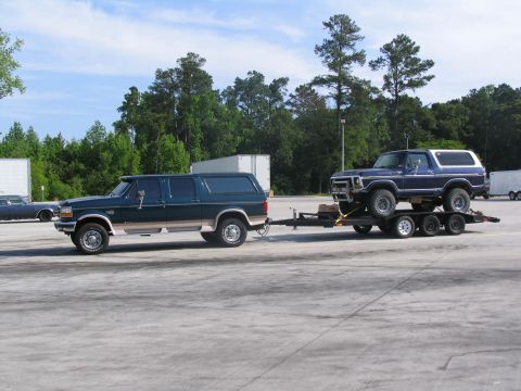 1978 Ford Bronco - A blue 1978 Ford Bronco is transported on a trailer, towed by a dark green Ford SUV.