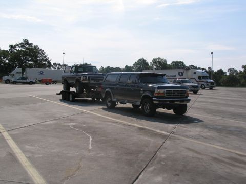 1978 Ford Bronco - A dark blue Ford Bronco is being towed by another dark blue Ford Bronco in a parking lot.