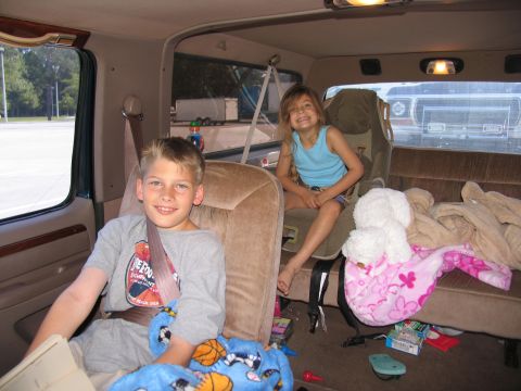 1978 Ford Bronco - Two children sit in the back of a van, with another vehicle visible through the rear window.
