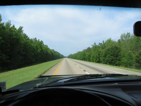 1978 Ford Bronco - Driving down a highway with trees on either side under a cloudy sky.