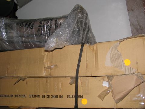1995 Ford C-350 (Centurion Conversions) - A vehicle part, likely a suspension component, is packaged for shipping on top of cardboard boxes.