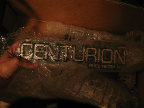 1995 Ford C-350 (Centurion Conversions) - A chrome Centurion emblem with "White Pigeon, MI" text is shown, likely a vehicle part.