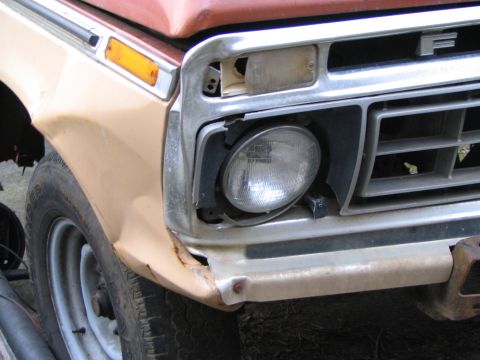 1983 Ford Bronco - The front end of a Ford F-Series truck shows damage to the headlight and bumper area, with a visible 'F' emblem on the grille.