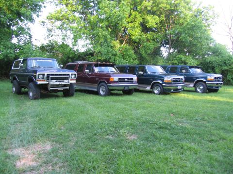 1995 Ford C-350 (Centurion Conversions) - A lineup of four extended SUVs, likely modified Ford Broncos or similar, are parked on a grassy lawn.