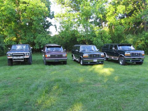 1995 Ford C-350 (Centurion Conversions) - Four Ford SUVs, including two 1995 Centurion Conversions, are parked on a grassy lawn with trees in the background.