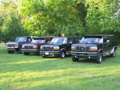 1995 Ford C-350 (Centurion Conversions) - A line of Ford Bronco/F-Series SUVs from the early to mid-1990s are parked on a grassy lawn.