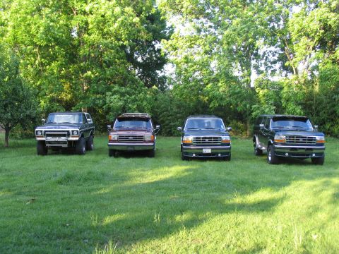 1995 Ford C-350 (Centurion Conversions) - Four SUVs, including two Ford Broncos and two Ford F-Series based conversions, are parked on a grassy lawn.