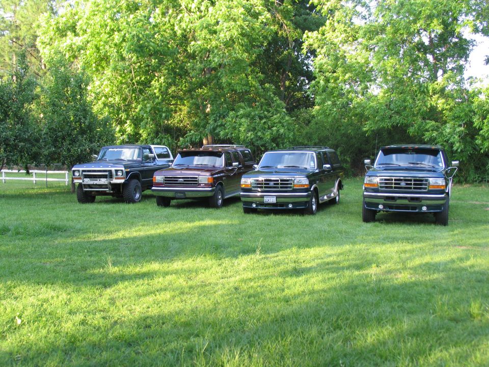 Four Ford Centurion Conversions SUVs parked in a grassy area with trees in the background. The front vehicles appear to be 1995 models