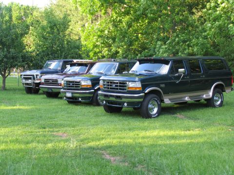 1995 Ford C-350 (Centurion Conversions) - Several Ford Centurion Conversion SUVs are lined up on a grassy area with trees in the background.