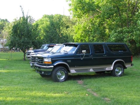 1995 Ford C-350 (Centurion Conversions) - Three SUVs are parked on a grassy lawn with trees in the background.