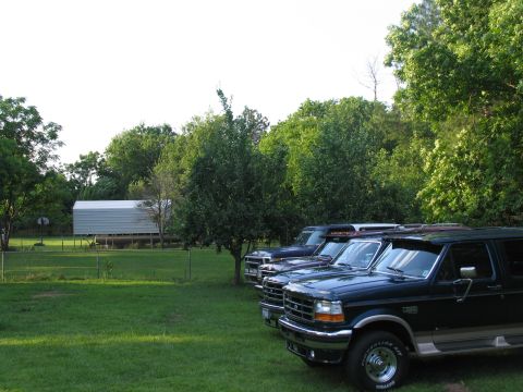 1995 Ford C-350 (Centurion Conversions) - Three Ford C-350 Centurion Conversions SUVs are parked in a yard on a sunny day.
