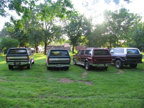 1995 Ford C-350 (Centurion Conversions) - A collection of SUVs, including a maroon Centurion conversion, are parked in a grassy area on a sunny day.