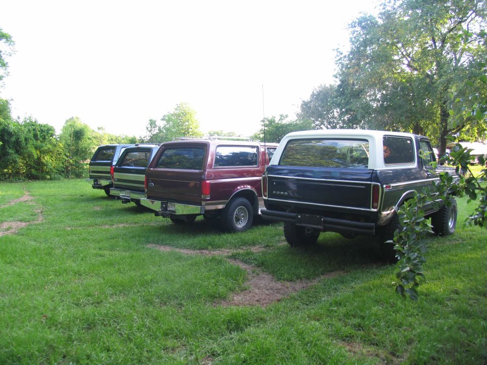 Dark blue and white Ford Bronco rear view, parked with three other Broncos